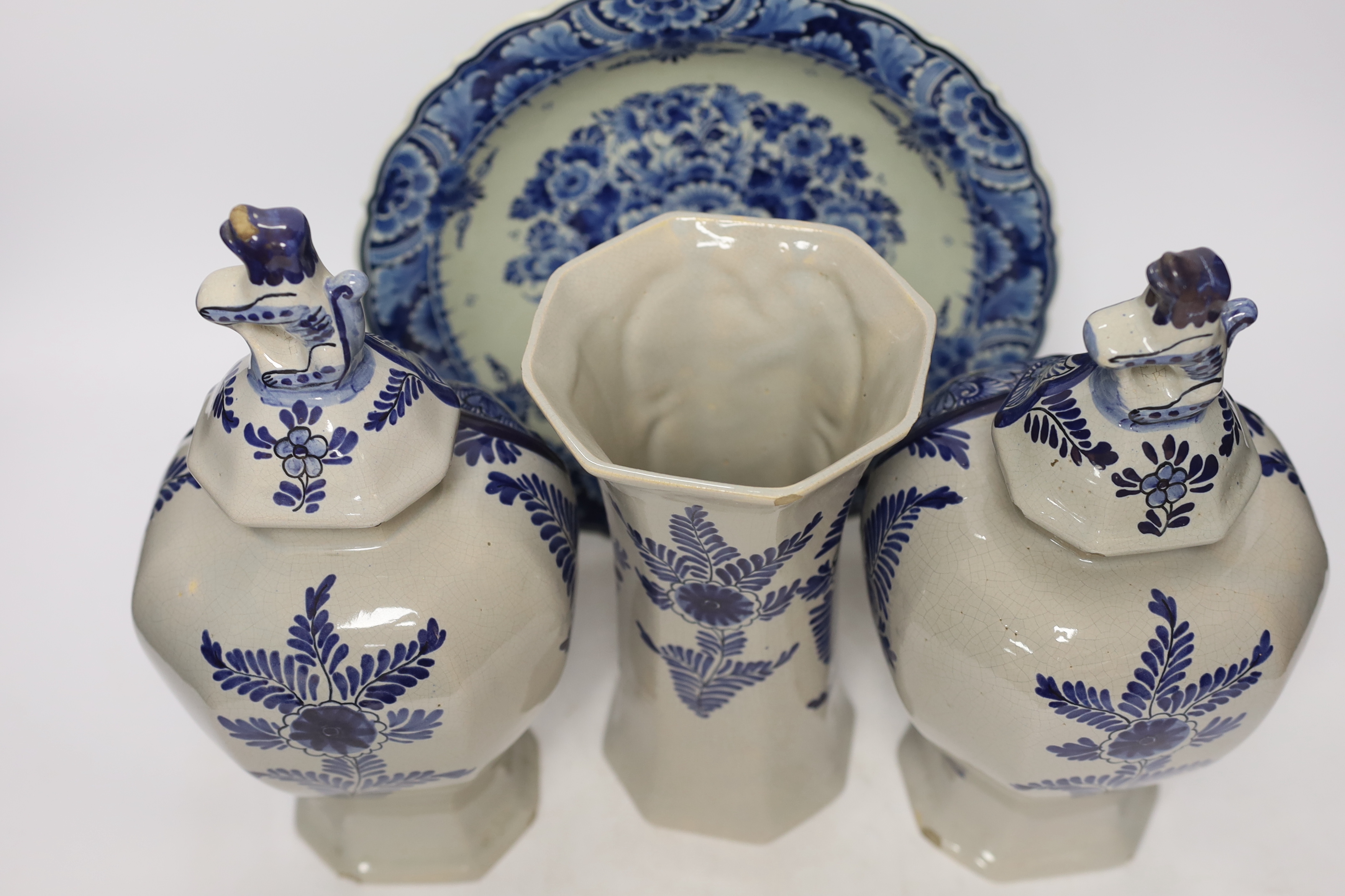 A late 18th century Delft garniture of three vases, two with covers, 32cm, together with a modern Delft plate